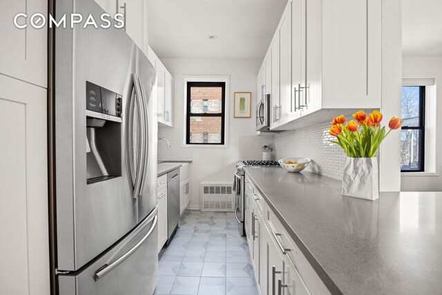 kitchen featuring dark countertops, tasteful backsplash, white cabinetry, and stainless steel appliances