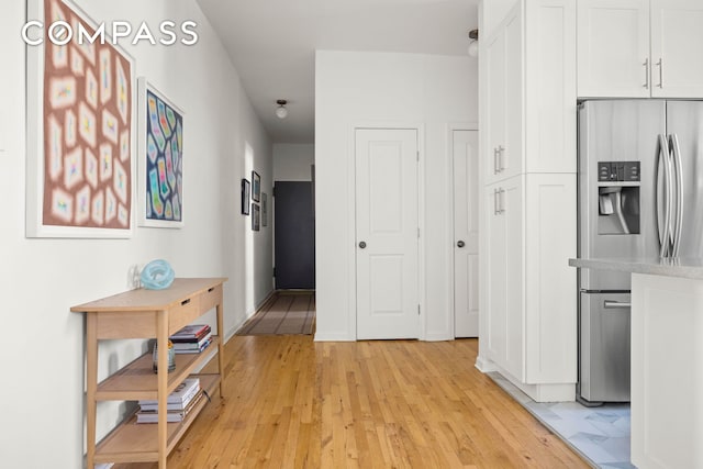 corridor with light wood-style flooring and baseboards