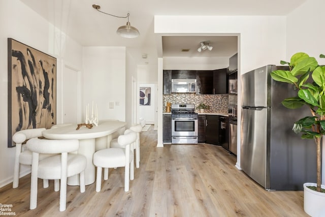 kitchen with stainless steel appliances, light wood-style floors, dark brown cabinets, light countertops, and tasteful backsplash