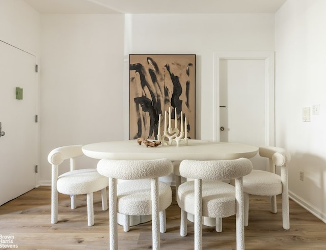 dining space with light wood-type flooring and baseboards