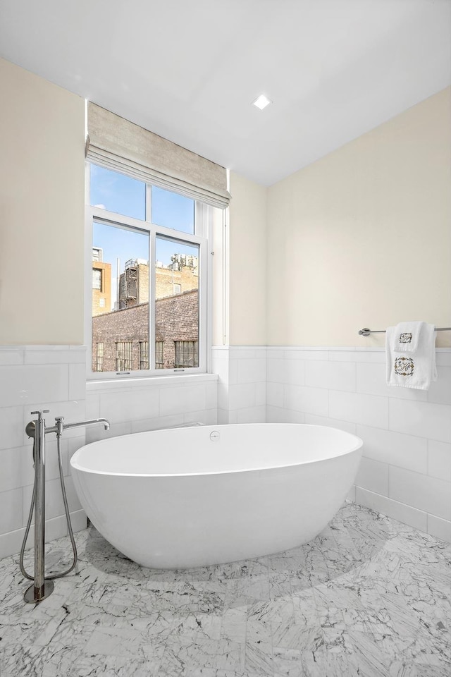 215 Sullivan St Unit 4A, New York City, NY 10012 - full bathroom with marble look tile flooring, wainscoting, a freestanding tub, and tile walls