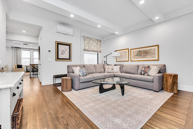 living room with an AC wall unit, beamed ceiling, and light wood-type flooring