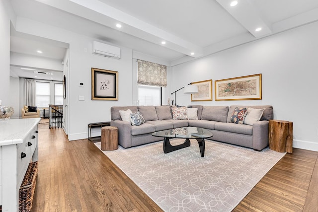 living area featuring a wall mounted air conditioner, beamed ceiling, baseboards, and wood finished floors