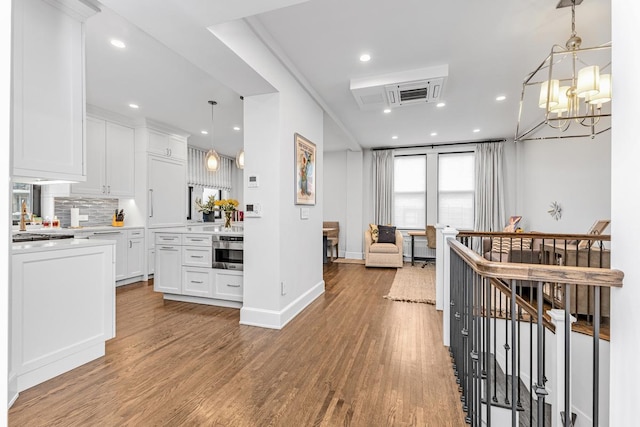 24 W 69th St Unit 9B, New York City, NY 10023 - kitchen featuring white cabinets, oven, light countertops, backsplash, and wood finished floors