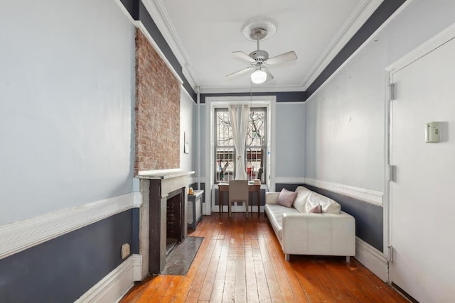 sitting room featuring hardwood / wood-style floors, ceiling fan, and crown molding