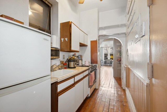 434 W 49th St Unit 1W, New York City, NY 10019 - kitchen with a sink, arched walkways, range with gas stovetop, freestanding refrigerator, and stainless steel microwave