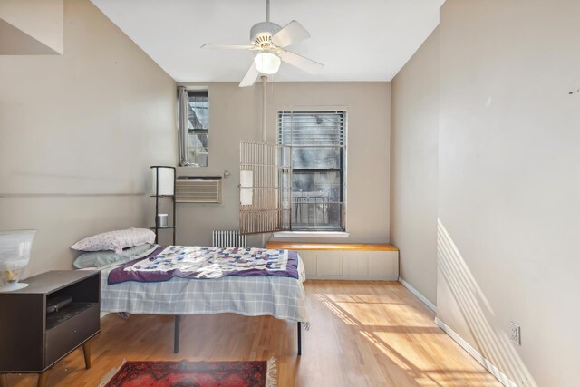 434 W 49th St Unit 1W, New York City, NY 10019 - bedroom featuring an AC wall unit, radiator, ceiling fan, and wood finished floors