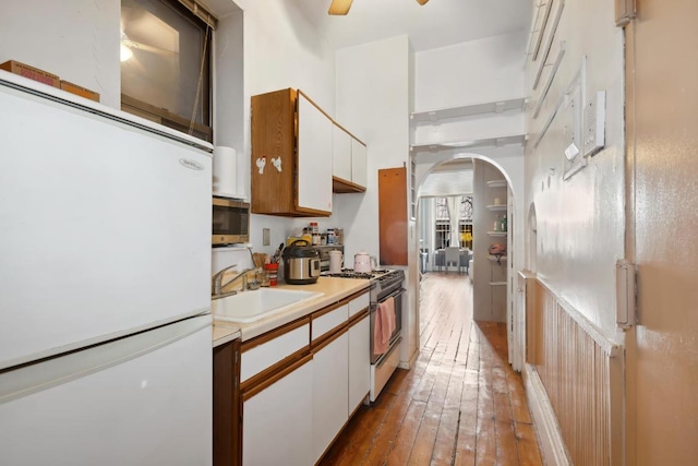 kitchen with appliances with stainless steel finishes, sink, ceiling fan, dark wood-type flooring, and white cabinets