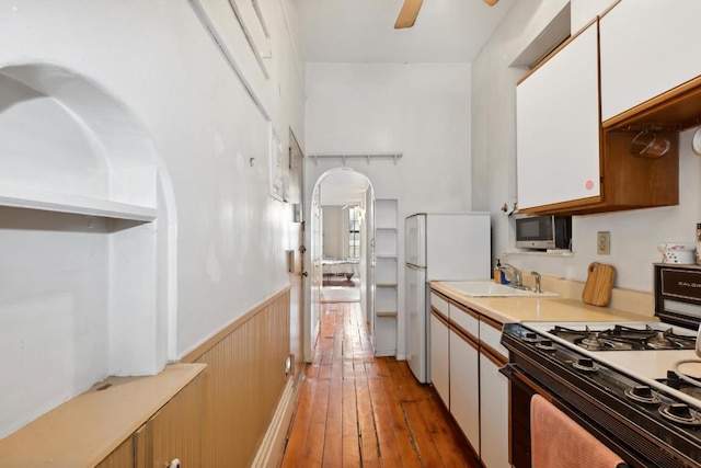 kitchen featuring sink, range with gas stovetop, ceiling fan, dark wood-type flooring, and white cabinets