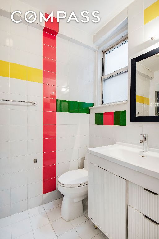 bathroom featuring tile patterned floors, tile walls, toilet, and vanity