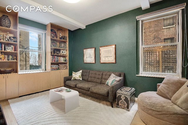 living area featuring beamed ceiling and wood finished floors