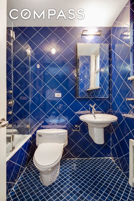 full bathroom featuring toilet, tile patterned flooring, and tile walls