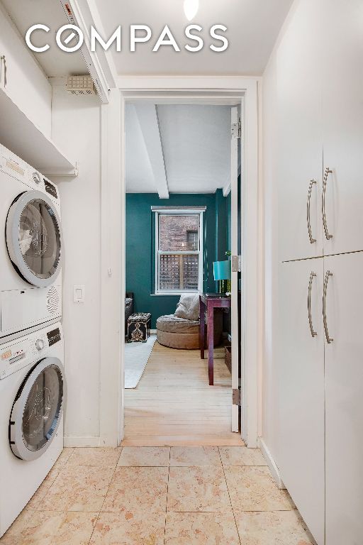 washroom featuring stacked washer and dryer, light tile patterned floors, and laundry area