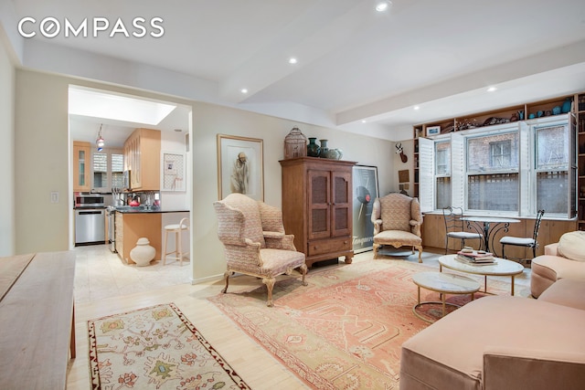 living area with light wood-style floors, a skylight, beamed ceiling, and recessed lighting