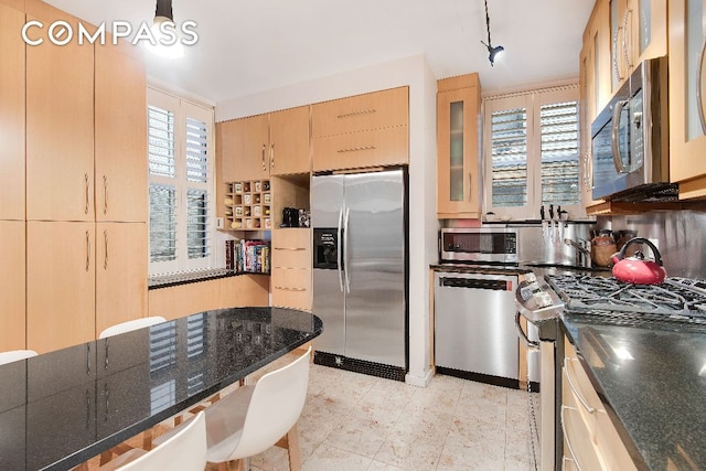 kitchen with stainless steel appliances, light brown cabinetry, plenty of natural light, and glass insert cabinets