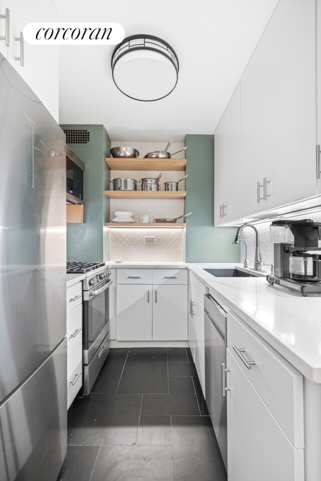 333 E 66th St Unit 5R, New York City, NY 10065 - kitchen with appliances with stainless steel finishes, open shelves, white cabinetry, and dark tile patterned floors