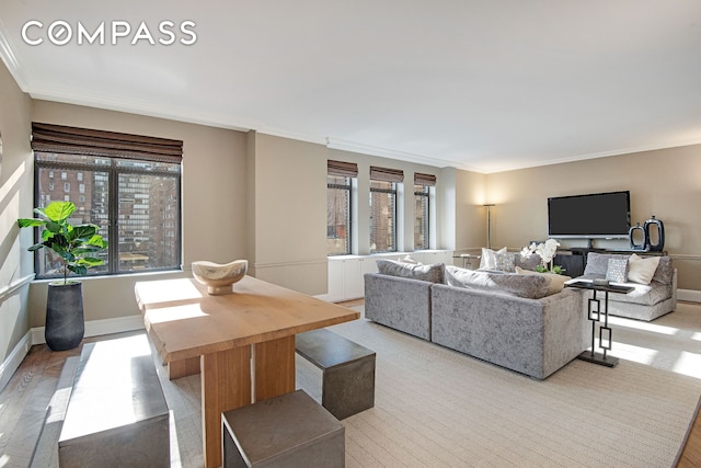 living area featuring crown molding, plenty of natural light, light wood finished floors, and baseboards