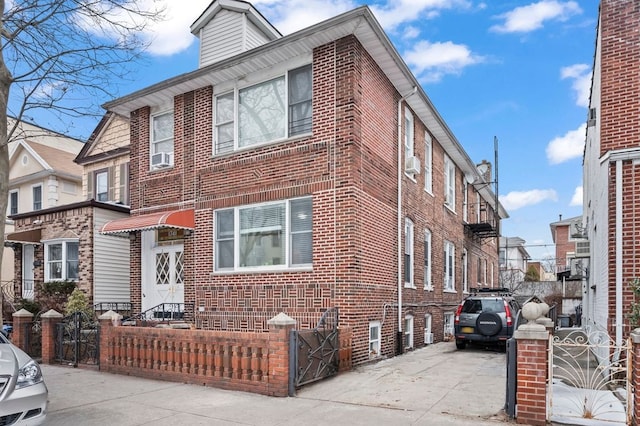 view of front facade featuring a fenced front yard, cooling unit, concrete driveway, and brick siding