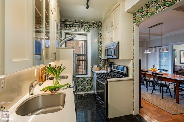 kitchen with decorative light fixtures, a sink, light countertops, appliances with stainless steel finishes, and glass insert cabinets