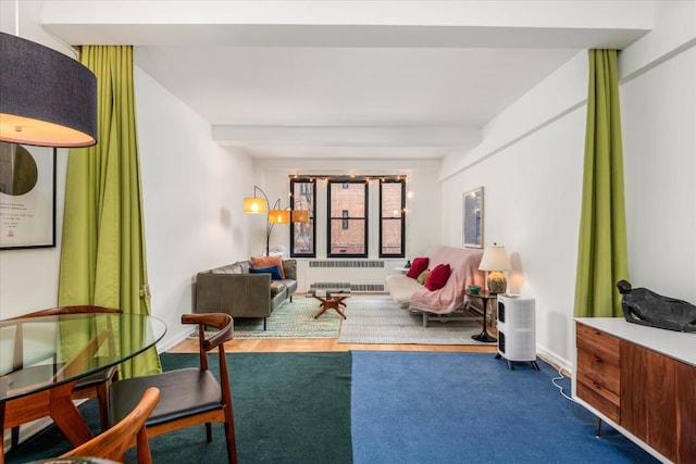 living area featuring radiator heating unit and beam ceiling