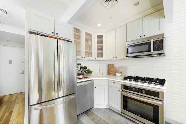 kitchen featuring glass insert cabinets, white cabinetry, appliances with stainless steel finishes, and light countertops