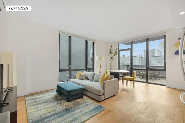 living area with baseboards, light wood-type flooring, visible vents, and floor to ceiling windows