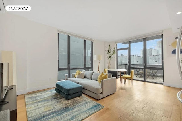 living room with light wood-style flooring, visible vents, a wall of windows, and baseboards