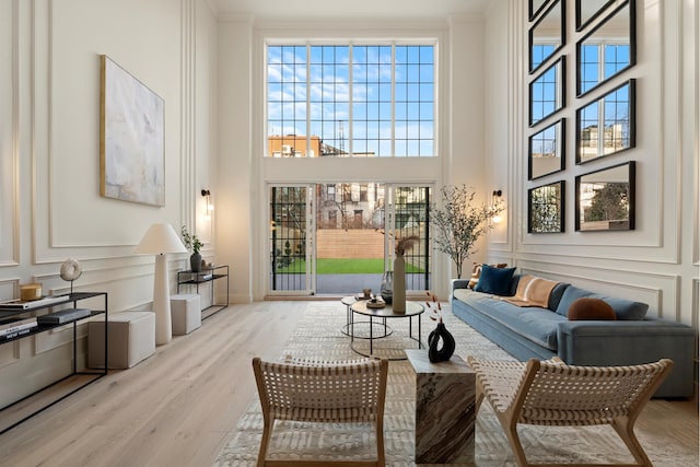 living area with wood finished floors, a towering ceiling, and a decorative wall