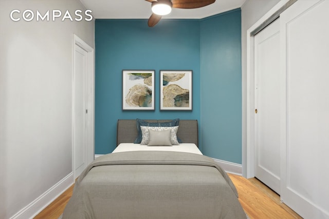 bedroom with ceiling fan, baseboards, wood finished floors, and a closet