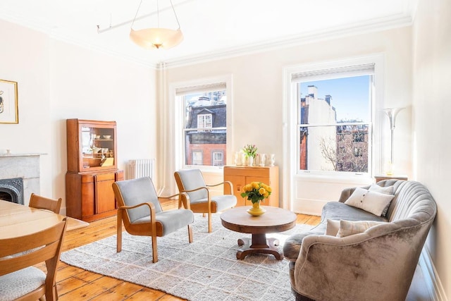 living area featuring ornamental molding, a tile fireplace, wood-type flooring, and a wealth of natural light