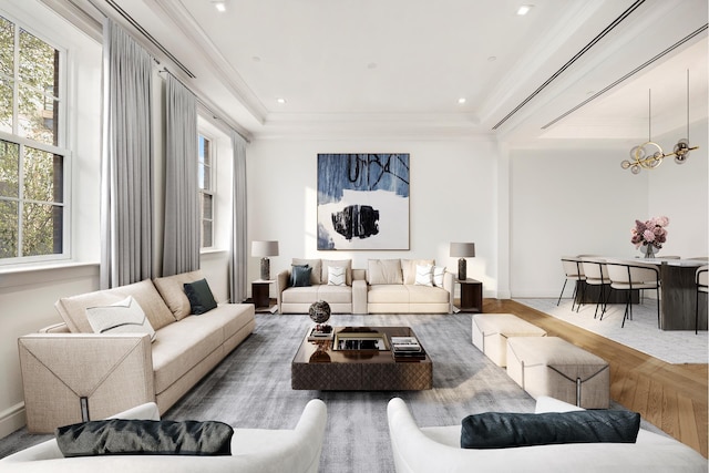 living room with a notable chandelier, a tray ceiling, wood finished floors, and a wealth of natural light