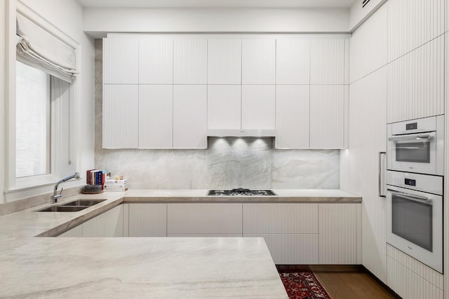 kitchen with a sink, white cabinetry, stainless steel gas stovetop, tasteful backsplash, and modern cabinets