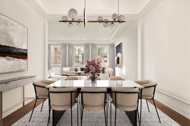 dining room with crown molding, a notable chandelier, baseboards, wood finished floors, and a tray ceiling