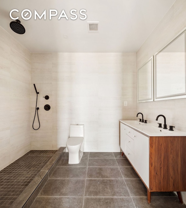 bathroom with visible vents, tile walls, tiled shower, tile patterned floors, and double vanity