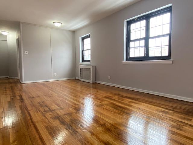 unfurnished room featuring radiator heating unit and wood-type flooring