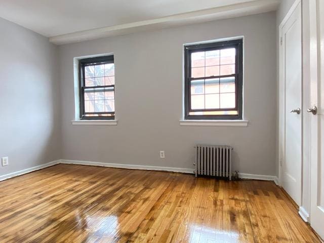 empty room with radiator heating unit and light hardwood / wood-style flooring