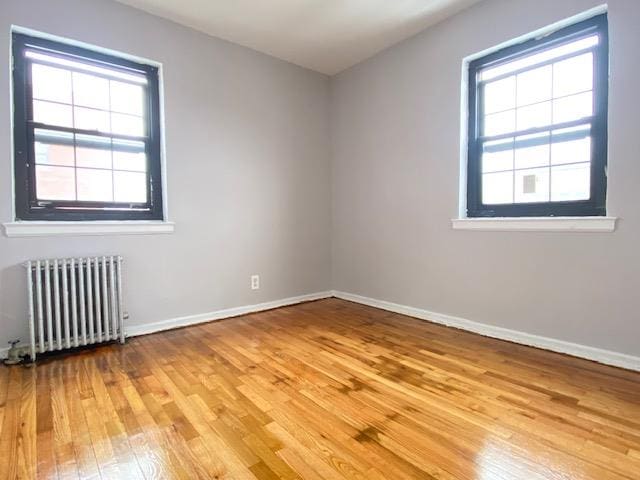 unfurnished room with radiator heating unit and light hardwood / wood-style floors