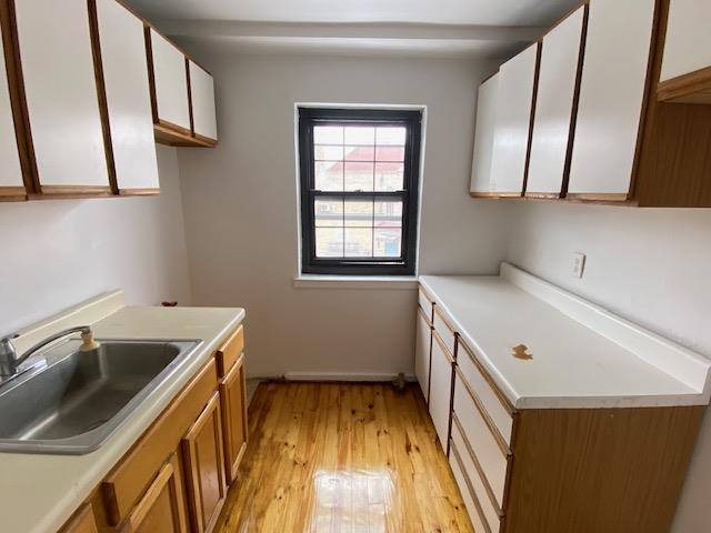 kitchen with sink, white cabinetry, and light hardwood / wood-style floors