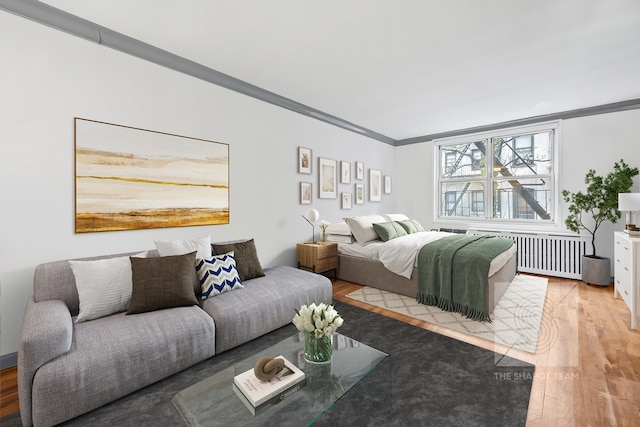 bedroom featuring light wood-type flooring, radiator heating unit, and ornamental molding