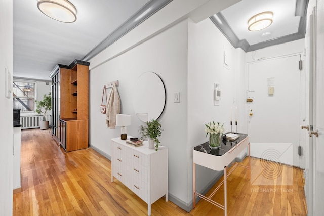 hallway with radiator, crown molding, and light hardwood / wood-style flooring