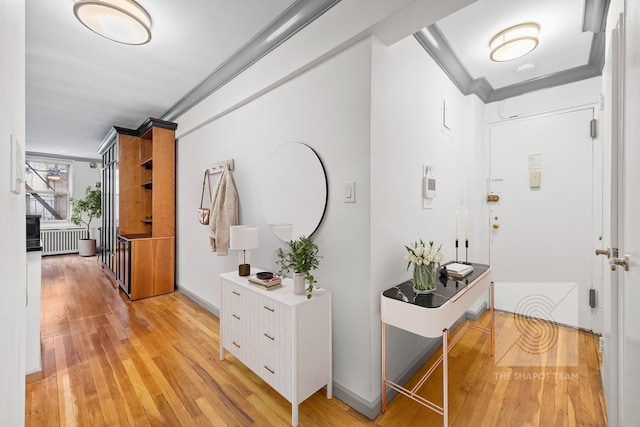 hallway with crown molding, light wood finished floors, and radiator heating unit