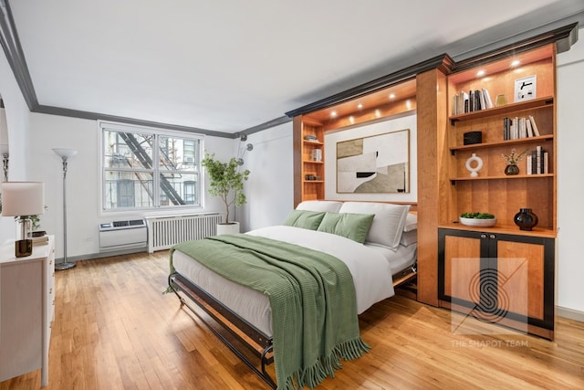 bedroom with crown molding, radiator heating unit, and light hardwood / wood-style flooring