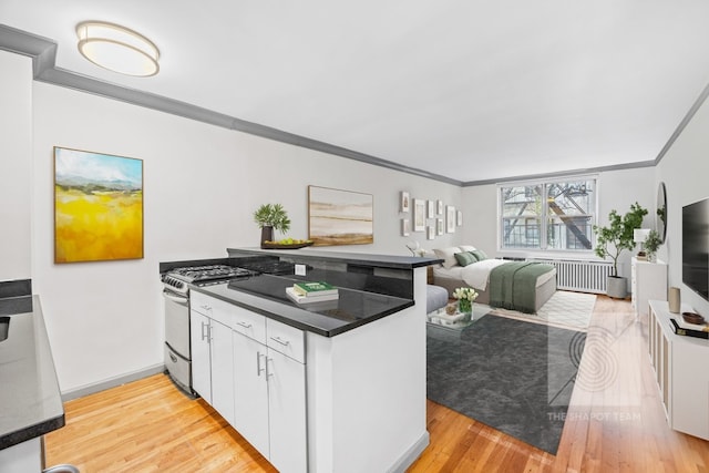 kitchen with stainless steel gas range oven, light hardwood / wood-style floors, crown molding, white cabinetry, and kitchen peninsula