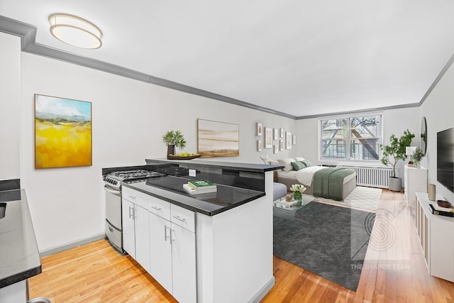 345 E 54th St Unit 3C, New York City, NY 10022 - kitchen with gas range, a peninsula, white cabinets, ornamental molding, and light wood finished floors