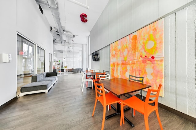 dining room with a high ceiling, wood finished floors, and baseboards