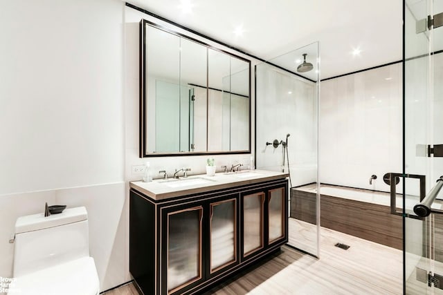 bathroom featuring a sink, double vanity, a shower stall, and toilet