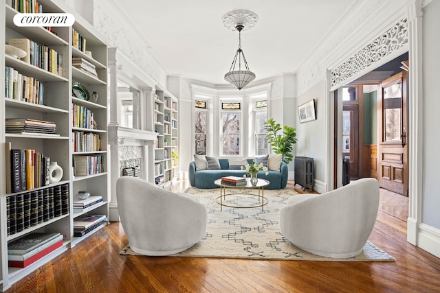 living area featuring crown molding, a fireplace, baseboards, and hardwood / wood-style floors