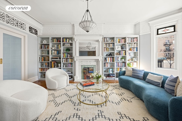 sitting room featuring wood finished floors, ornamental molding, a fireplace with flush hearth, and visible vents