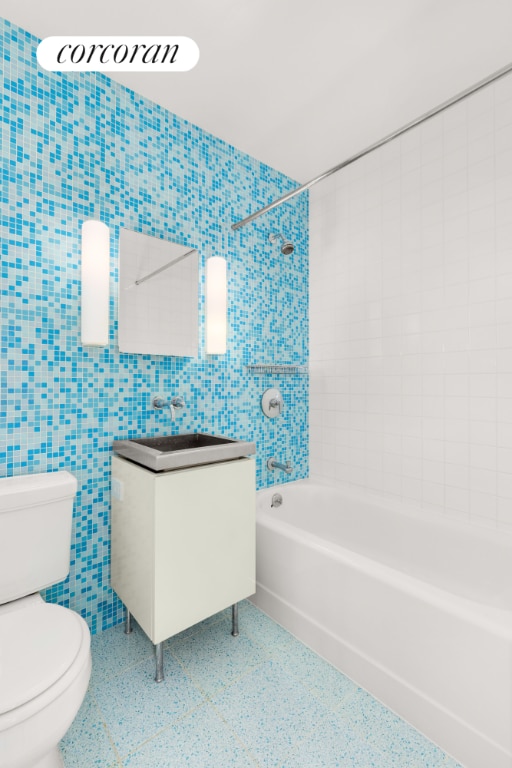 full bathroom featuring toilet, tile walls, tiled shower / bath combo, and vanity