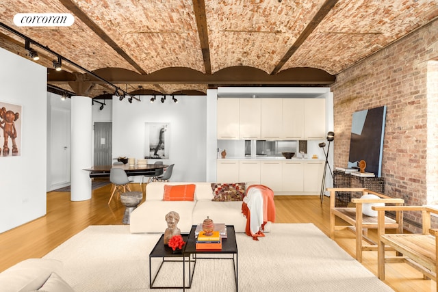 living area featuring visible vents, brick wall, brick ceiling, rail lighting, and light wood-type flooring